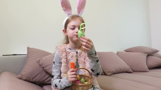 Chica-con-orejas-de-conejo-y-huevos-de-Pascua-decorativos-comer-zanahoria