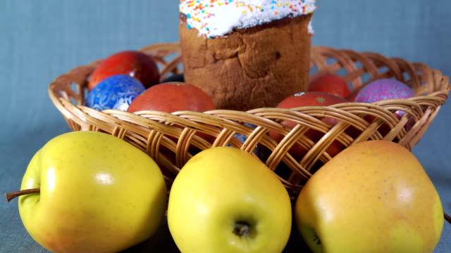 Close-up,-Easter-Arrangement,-Easter-in-the-Wooden-Basket-with-Dyed-Eggs-and-Apple-on-the-Background