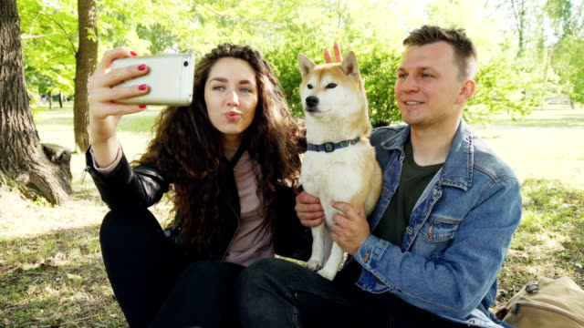 Stolzer-Hund-Besitzer-Brautpaar-nehmen-Selfie-mit-schönen-Tier-Spaß-und-Getue-es-Smartphone-betrachten.-Moderner-Lifestyle,-Tiere-und-Technik-Konzept.