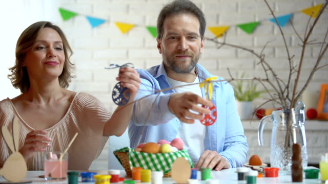 Mann-und-Frau-Vorbereitung-Oster-Deko,-Spielzeug-Eier-auf-Ast-hängend