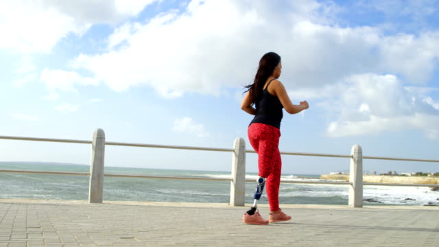 Vista-lateral-de-movilidad-mujer-caminando-en-el-paseo-marítimo-4k