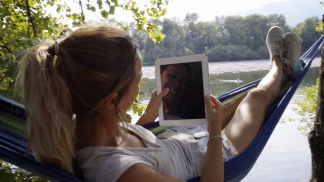 Junge-Frau-mit-digital-Tablette-auf-Hängematte