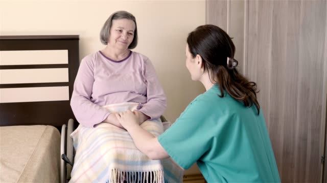 Ältere-Frau-auf-Rollstuhl-im-Pflegeheim-mit-ihrer-Pflegeassistentin