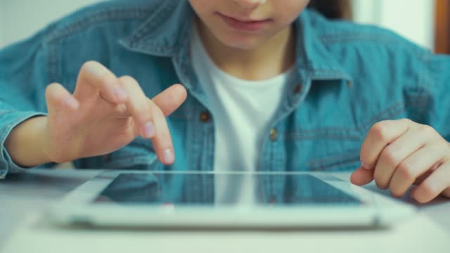 closeup-of-little-girl-hands-in-jeans-wear-playing-games-on-tablet