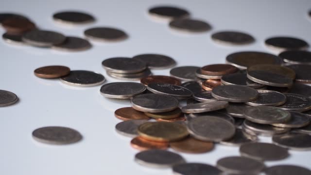 close-up-4k-motion-footage-of-money-coins-falling-to-pile-of-coins-on-white-floor.-business,-financial-for-money-saving-or-investment-concept