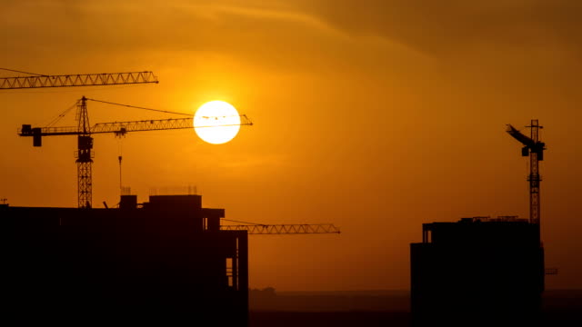 The-building-with-cranes-on-the-sunset-background.-time-lapse