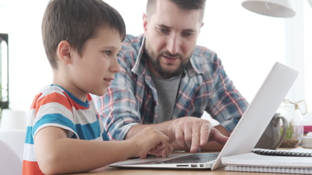 Father-guiding-his-son-to-use-laptop