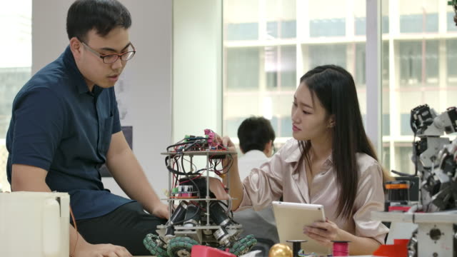 Equipo-de-ingenieros-electrónicos-trabaja-con-robot,-construcción,-fijación-de-robótica-en-taller.-Personas-con-concepto-de-tecnología-o-innovación.