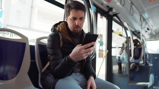 Mann-fährt-Bus-und-schaut-auf-dem-Bildschirm-des-Smartphones