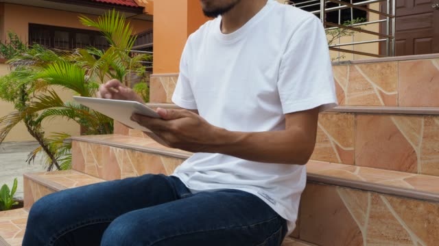Hombre-sosteniendo-usando-el-juego-de-la-tableta-en-línea-en-casa