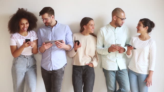 Glückliche-verschiedene-junge-Freunde-stehen-in-Reihe-sprechen-Handys