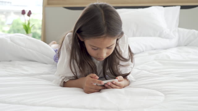 Asiatische-Mädchen-mit-Smartphone-im-Schlafzimmer