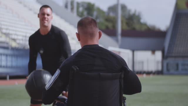Atleta-en-silla-de-ruedas-y-entrenador-lanzando-pelota-de-medicina