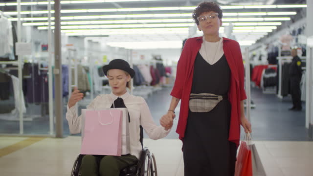 Glückliche-Frau-im-Rollstuhl-und-ihre-Freundin-Einkaufen