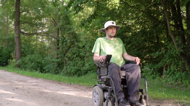Slowmotion-follow-of-disabled-young-man-in-a-wheelchair-observing-nature-around-him