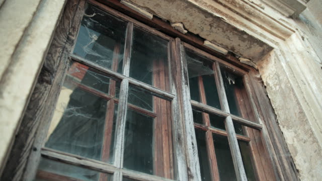 antique-wooden-window,-on-a-gray-shabby-building,-around-cobwebs-and-dirt