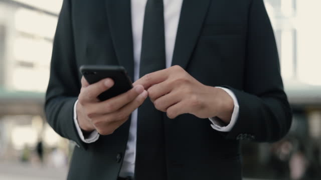 Asian-businessman-using-a-smartphone-browsing-social-media-and-sending-message-to-employees-in-the-office.-Close-up-hand-asian-man-using-smartphone-typing-on-its-screen-while-chatting-with-friends.