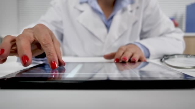 mujer-doctora-que-trabaja-en-su-escritorio-analizando-rayos-X-mri-cerebro-en-la-tableta-de-la-computadora
