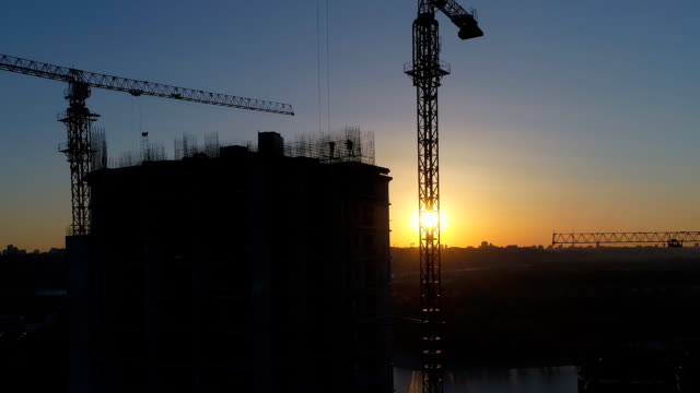 Aerial-shot-of-construction-site-with-cranes-and-workers-at-sunset