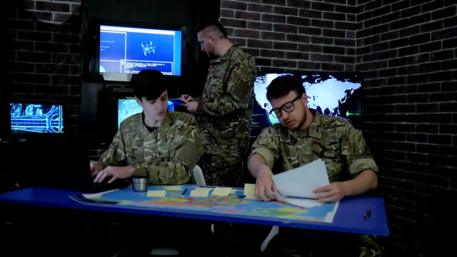 Soldat-in-Tarnuniform,-Karten-und-arbeiten-in-Laptoop,-militärisches-Hauptquartier-briefing-im-Überwachungsraum