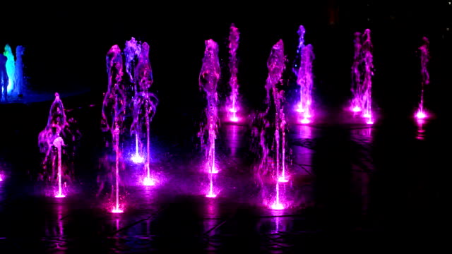 Fuente-iluminada-en-la-noche-con-púrpura