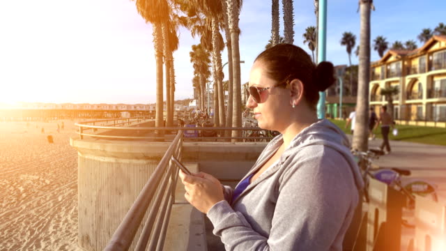 Video-of-woman-using-mobile-phone-on-the-boardwalk-in-4K