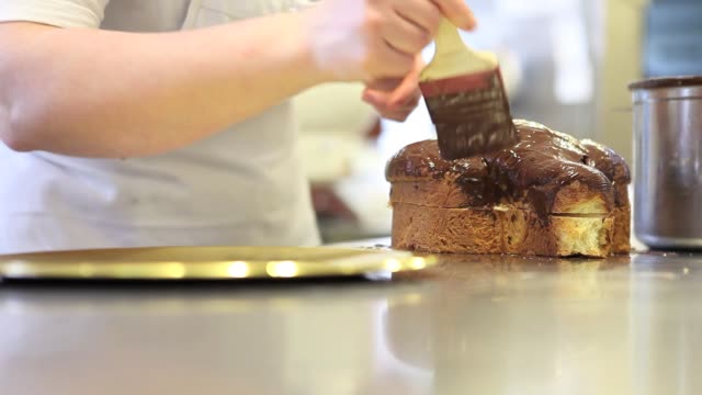 pastry-chef--hands-glazed-Easter-sweet-bread-cakes-with-chocolate,-closeup-on-the-worktop-in-confectionery