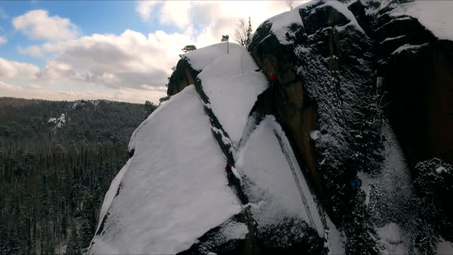 Luftaufnahme-von-einem-Kletterer-Klettern-steile-Klippen-bei-einem-sonnigen-Wintertag.