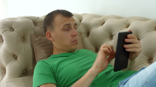 Hombre-alegre-websurfing-con-pc-de-la-tableta-en-el-sofá