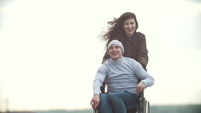 Happy-behinderte-Menschen-im-Rollstuhl-mit-glückliche-junge-Frau-läuft-auf-der-Stadtstraße