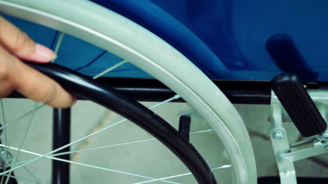 Close-up-Hand-mit-Rollstuhl-Patienten-alleine-fahren