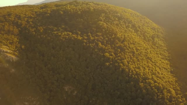 Luftbild-Drohnenflug-über-die-Felskante-Berg-hoch-oben-mit-Sonnenuntergang-massive-Wald