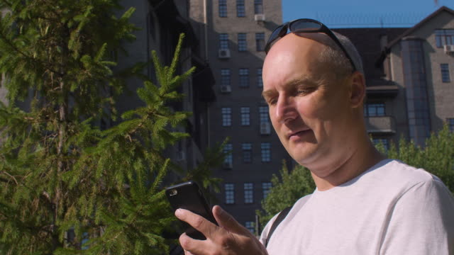 Erwachsenen-Mannes-in-Sonnenbrille-SMS-im-Chat-auf-Smartphone-in-Stadt