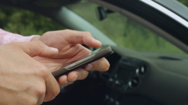 Männliche-Hände-SMS-auf-Handy-in-der-Nähe-von-Auto