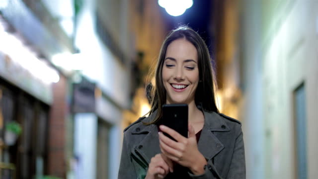 Mujer-caminando-usando-un-teléfono-inteligente-en-la-noche