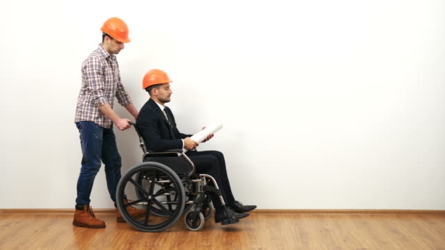 Der-Geschäftsmann-auf-dem-Rollstuhl-und-ein-Ingenieur-dikuss-mit-einer-Zeichnung