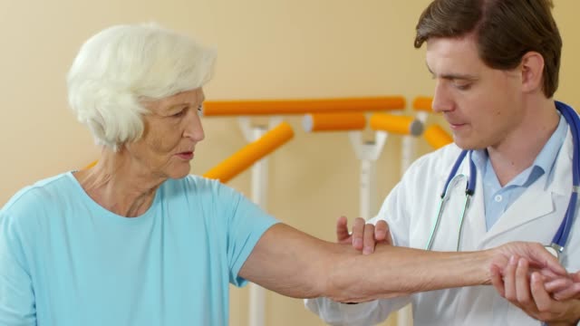 Fisioterapeuta-comprobando-la-sensibilidad-del-brazo-del-paciente-anciano