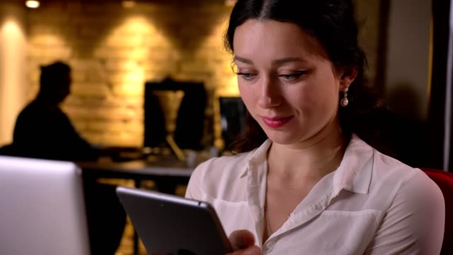 Closeup-of-young-caucasian-female-office-worker-using-the-tablet-getting-surprised-and-smiling-on-the-workplace-indoors