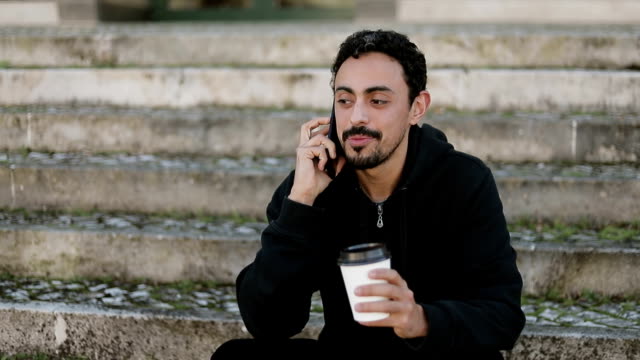 Mann-redet-am-Telefon-und-hält-Kaffee-in-der-Hand-draußen