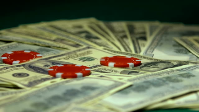 Casino-chips-falling-on-dollar-bills,-big-winnings,-jack-pot,-slow-motion