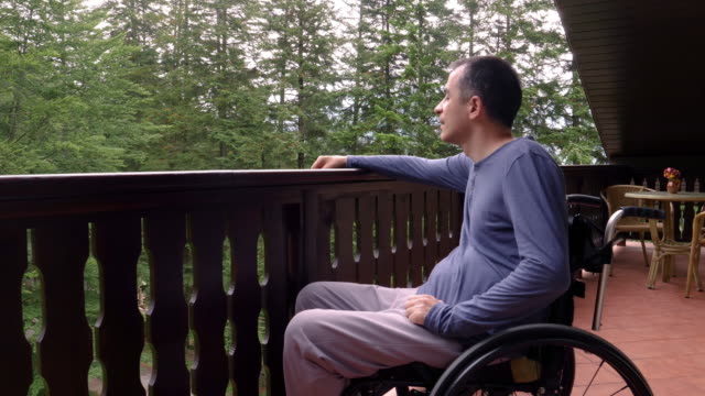 Junger-Mann-im-Rollstuhl-entspannt-auf-Terrasse