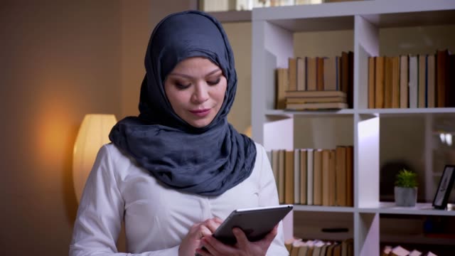 Tiro-de-primer-plano-de-mujer-empresaria-musulmana-adulta-usando-la-tableta-en-el-lugar-de-trabajo-en-el-interior