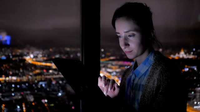 Mujer-usando-tableta-digital-negra-por-la-noche