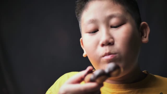 Asiatischer-Junge,-der-Donut-mit-geringem-Licht-und-Zeitlupe-isst.