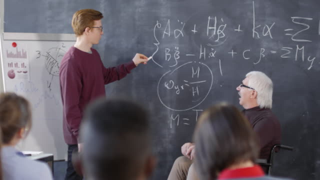 Student-und-Lehrer-diskutieren-Gleichung-am-Blackboard