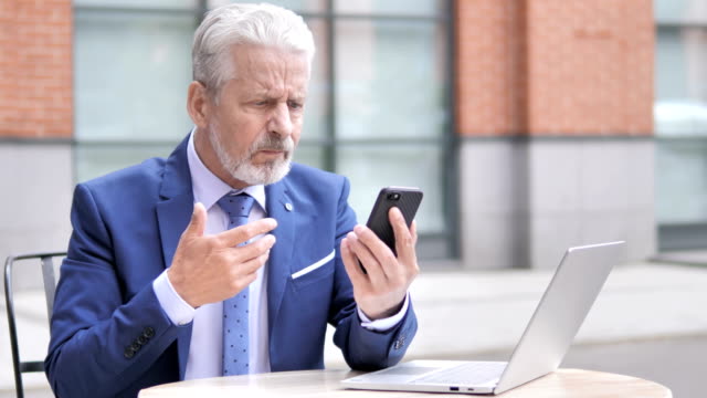 Old-Businessman-Upset-by-Loss-while-Using-Smartphone