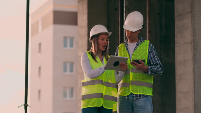Engineers-or-architects-have-a-discussion-at-construction-site-looking-through-the-plan-of-construction.-contre-jour.-Engineers-or-architects-have-a-discussion.