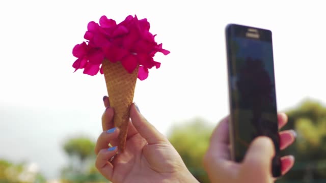 Woman-with-mobile-taking-picture-of-cone-flower-bouquet