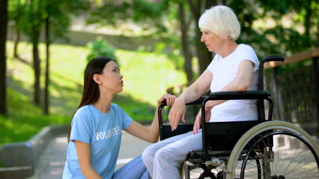 Weibliche-Freiwillige-trösten-weinende-alte-Dame-Rollstuhl,-Altersbehinderung,-Hilfe