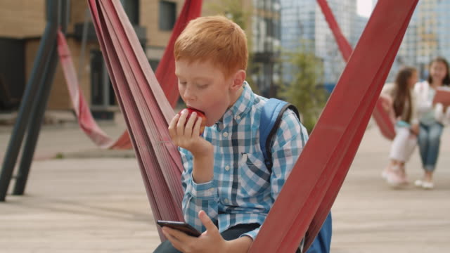 Schoolboy-Using-Phone-and-Having-Bite